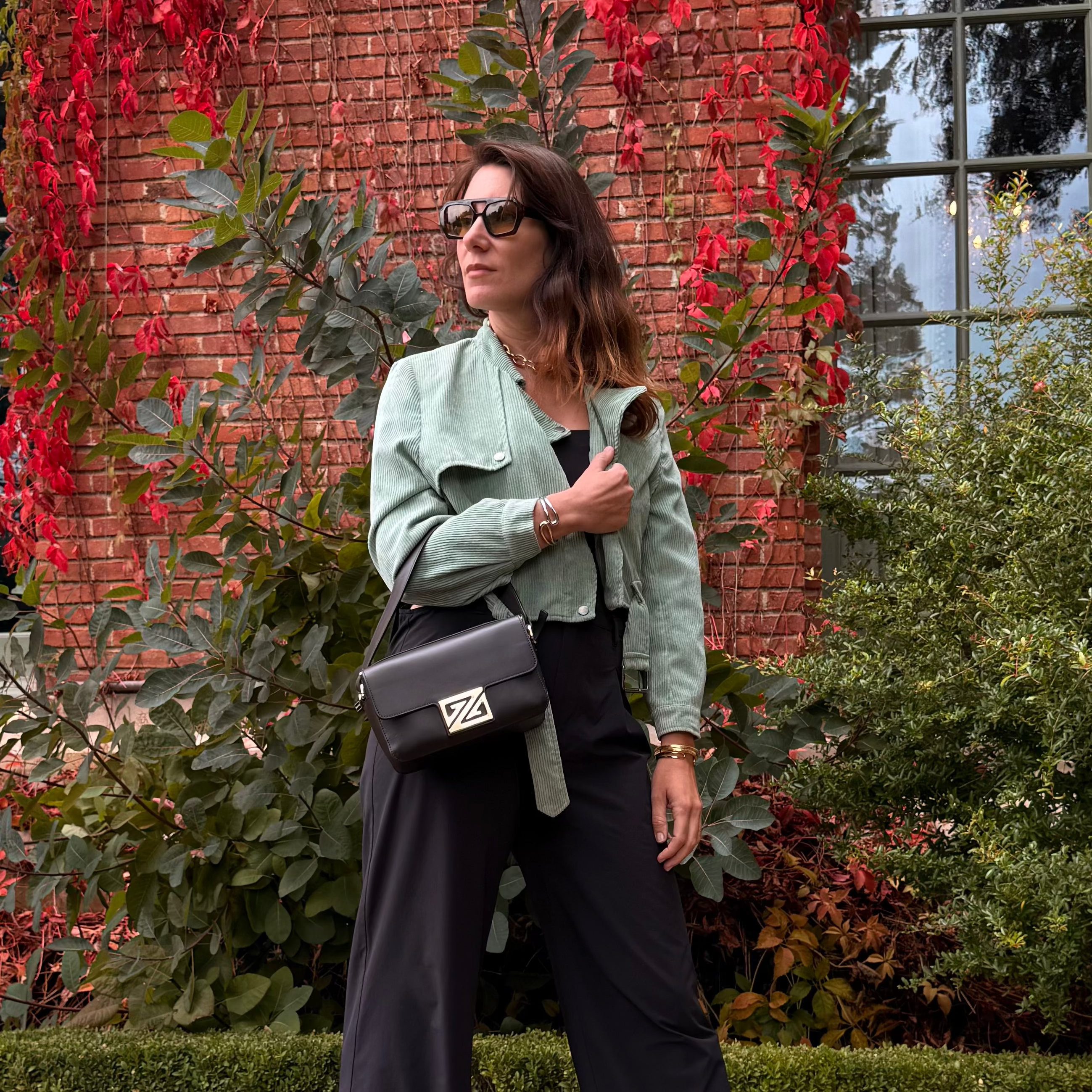 Model with a Picco XL standing in front of a brick wall with red foliage