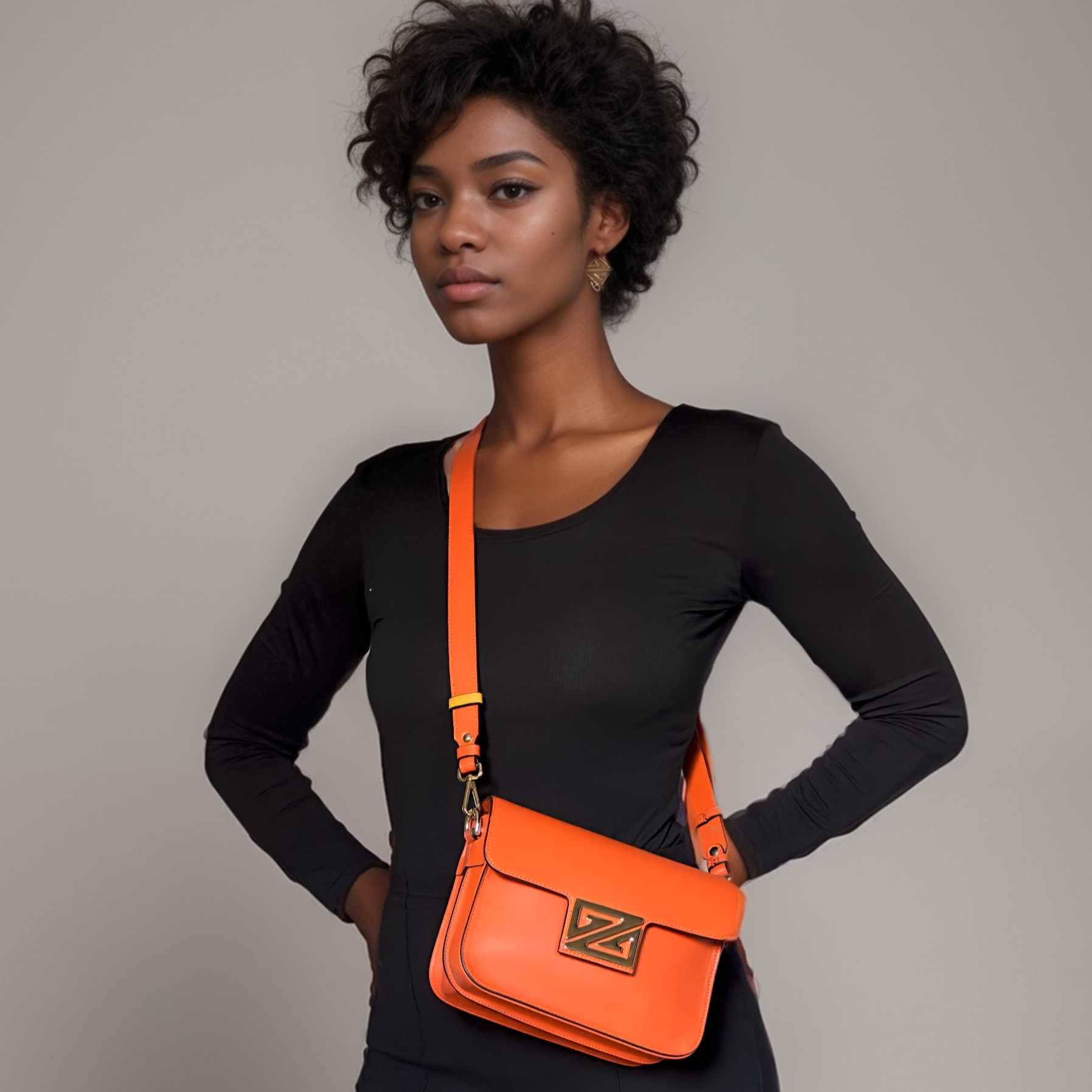Woman wearing a black outfit with an orange ZIPPERLY crossbody Mimi bag on a neutral background