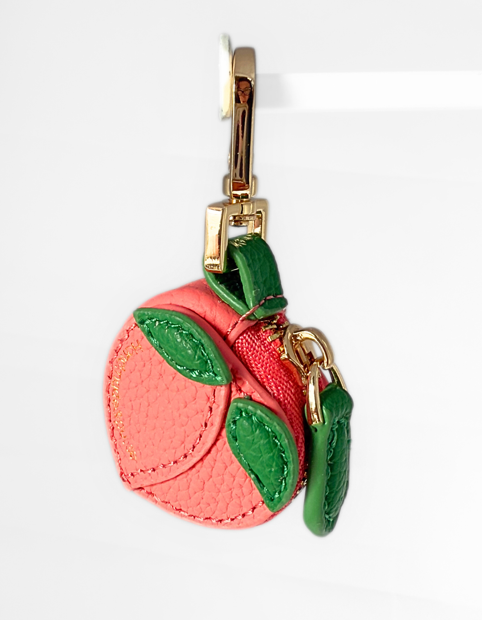 Pink Leather Peach-shaped Air tag keychain with green leaves on a white background