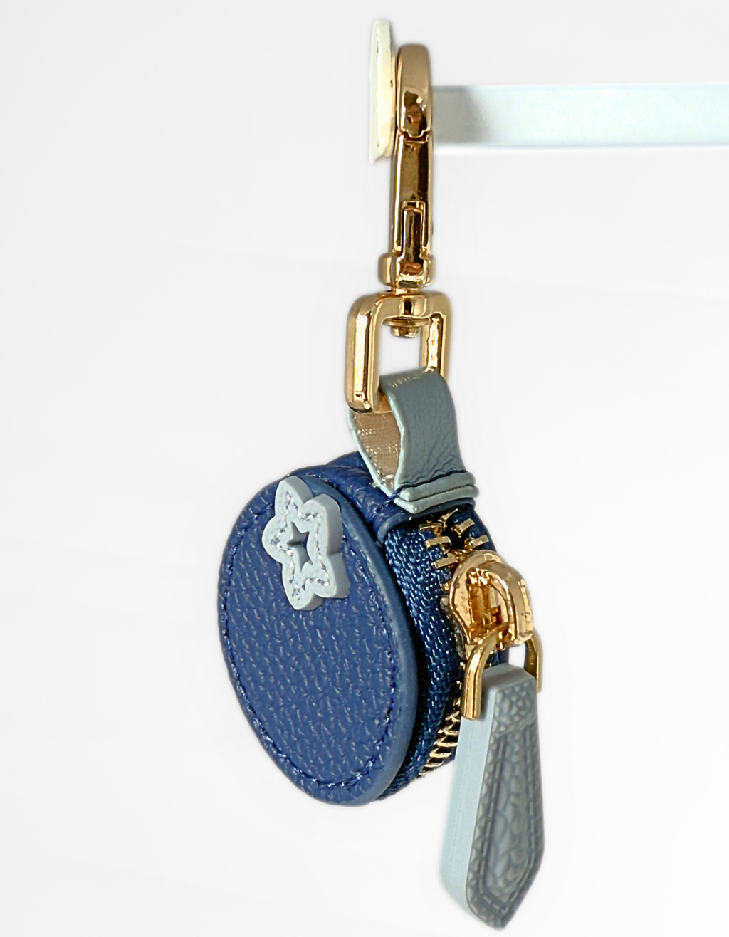 Leather Blue Blueberry Air tag pouch charm with gold zipper and star design on a white background