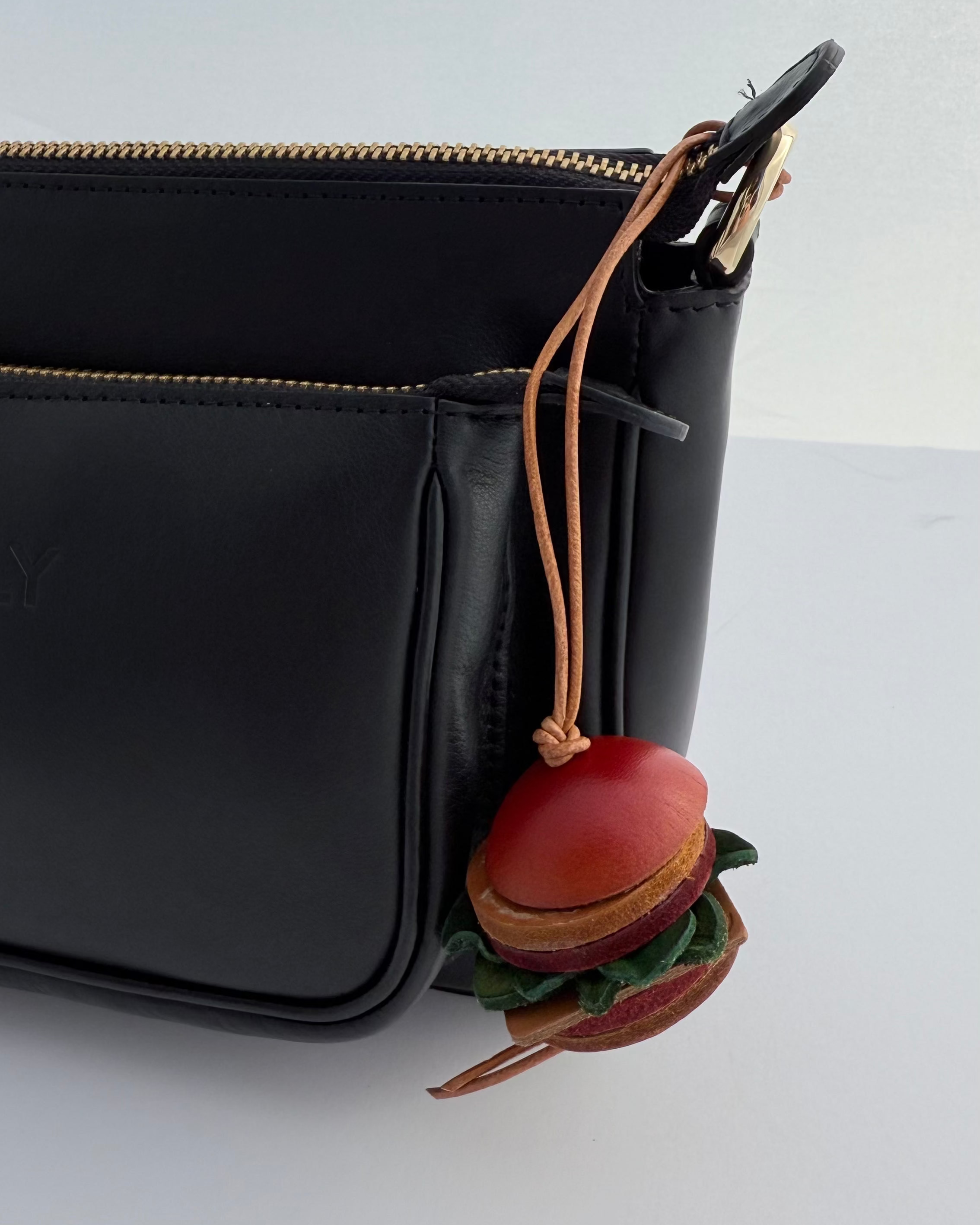 Black leather bag with a hamburger-shaped keychain on a white background