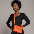 Woman wearing a black outfit with an orange ZIPPERLY crossbody Mimi bag on a neutral background