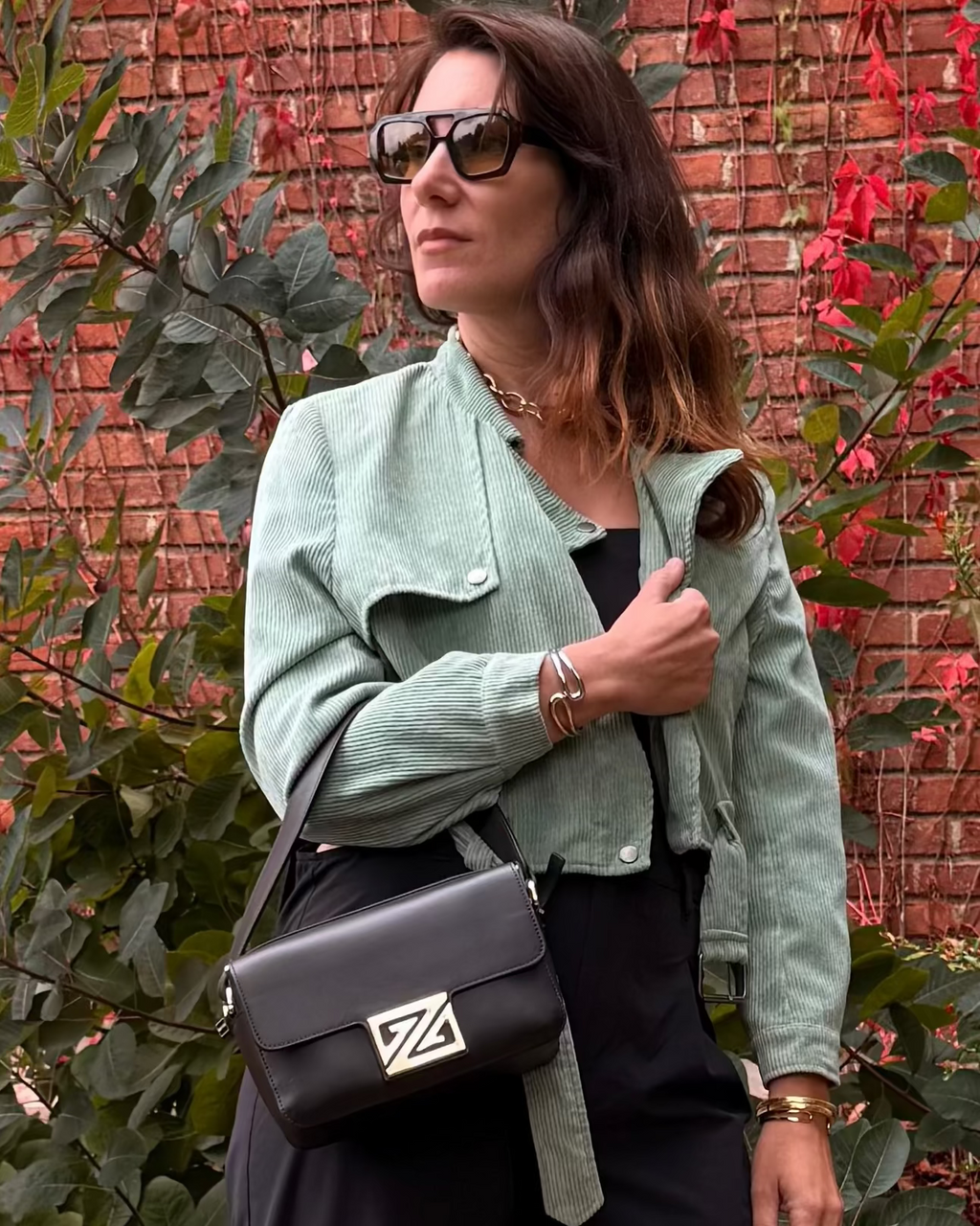 Model whholdingthe Picco XL handbag in the coffee color in front of a brick wall