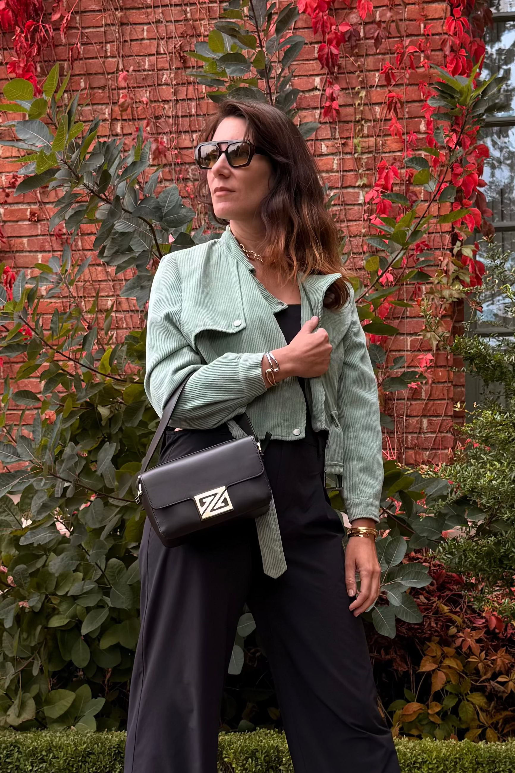 Model whholdingthe Picco XL handbag in the coffee color in front of a brick wall